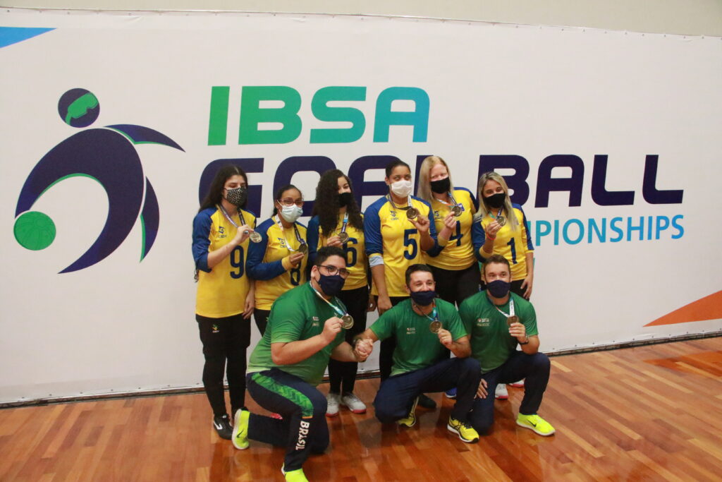 The Brazilian women's team and their coaches gather for a group photo and pose with their gold medal